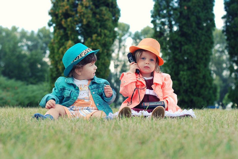 Two kids sitting in the grass dressed from the past