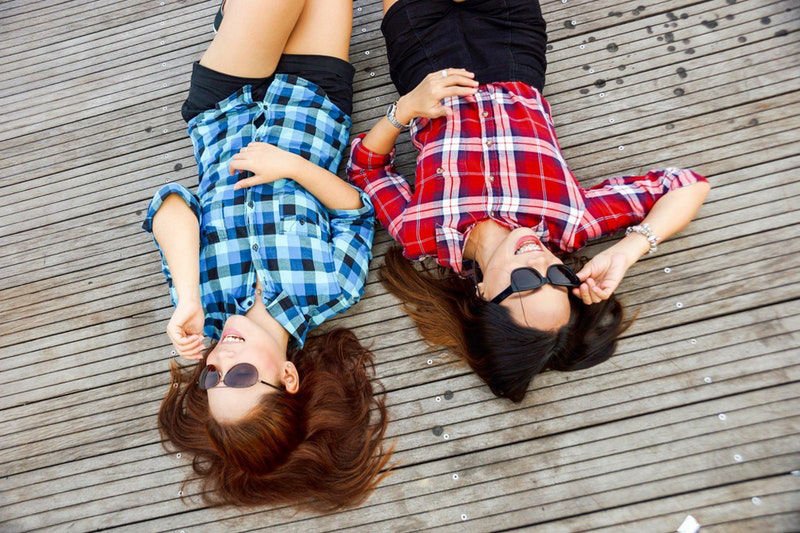 Two girls lying on a deck in the sun